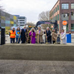 city and community members pose for photo at construction site.