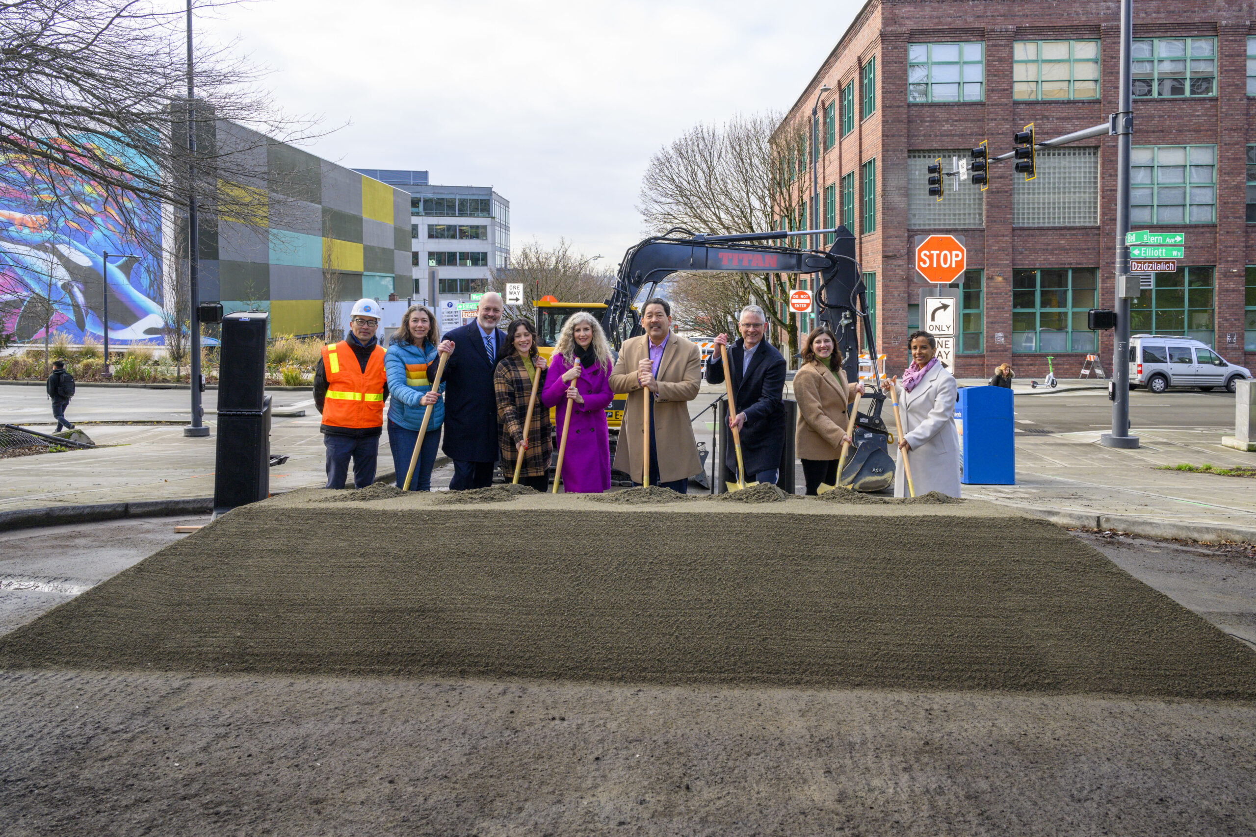 city and community members pose for photo at construction site.