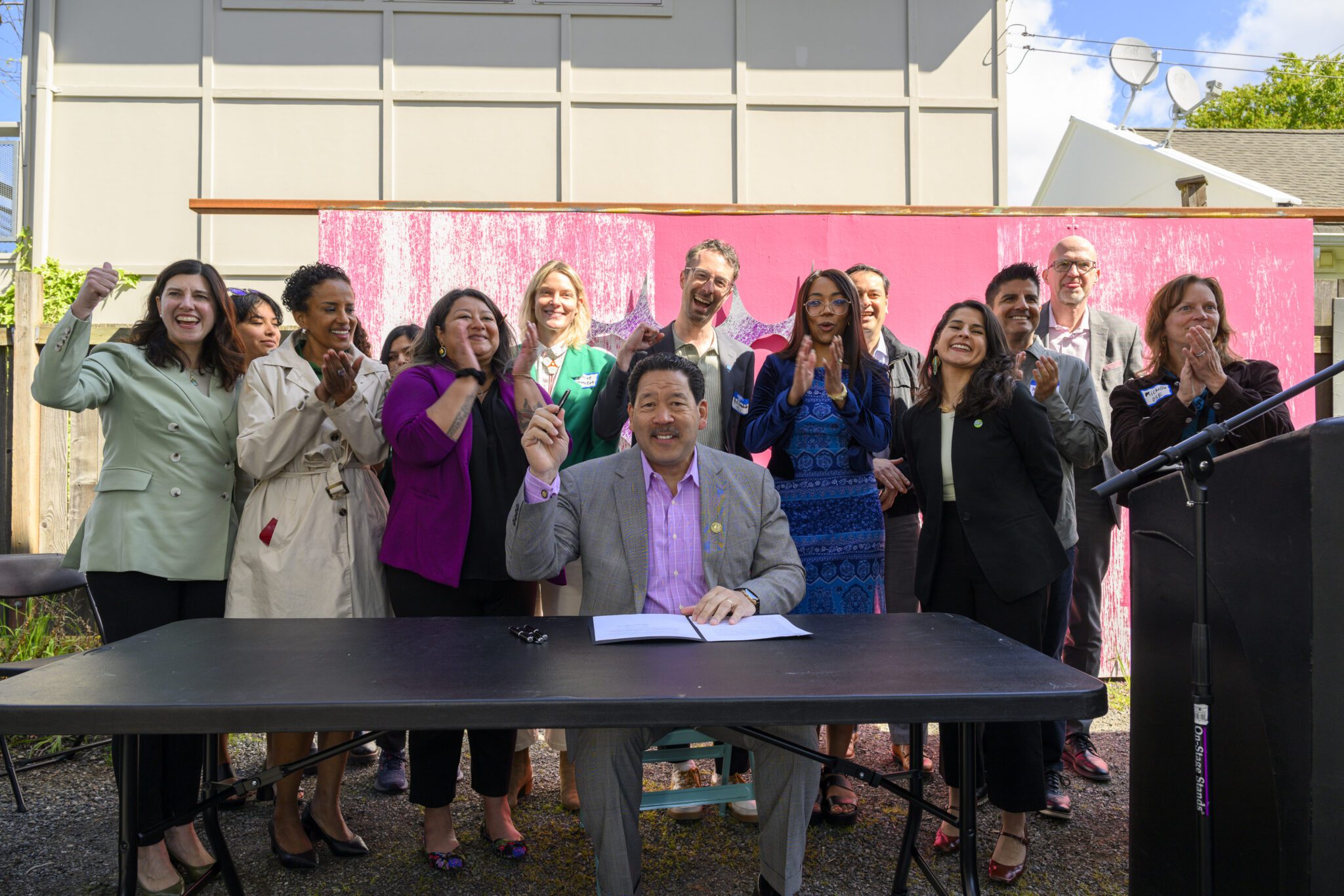 People clap and smile after Mayor Harrel signs the Earth Day Executive Order into law.