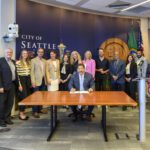 Mayor Harrell sings Sound Transit permitting legislation with leaders behind him.