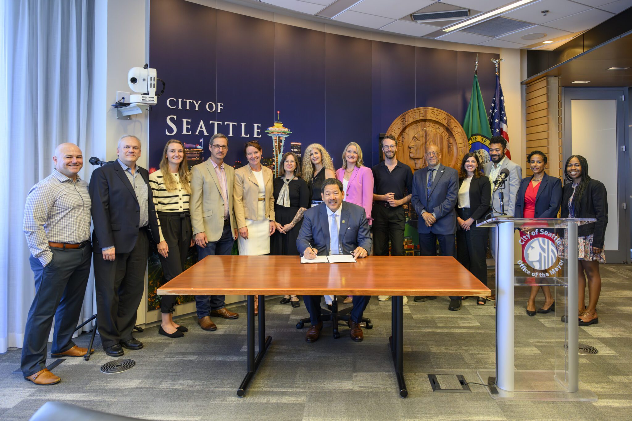 Mayor Harrell sings Sound Transit permitting legislation with leaders behind him.