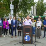 Mayor Harrell speaking at podium in Ballard with local elected, transportation, and labor leaders