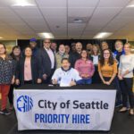 Mayor Harrell signs the directive with labor and community partners behind him.